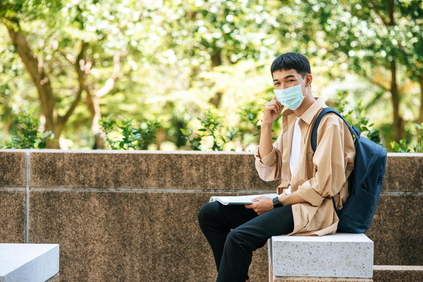 Men wearing masks sit reading books on the stairs. photo