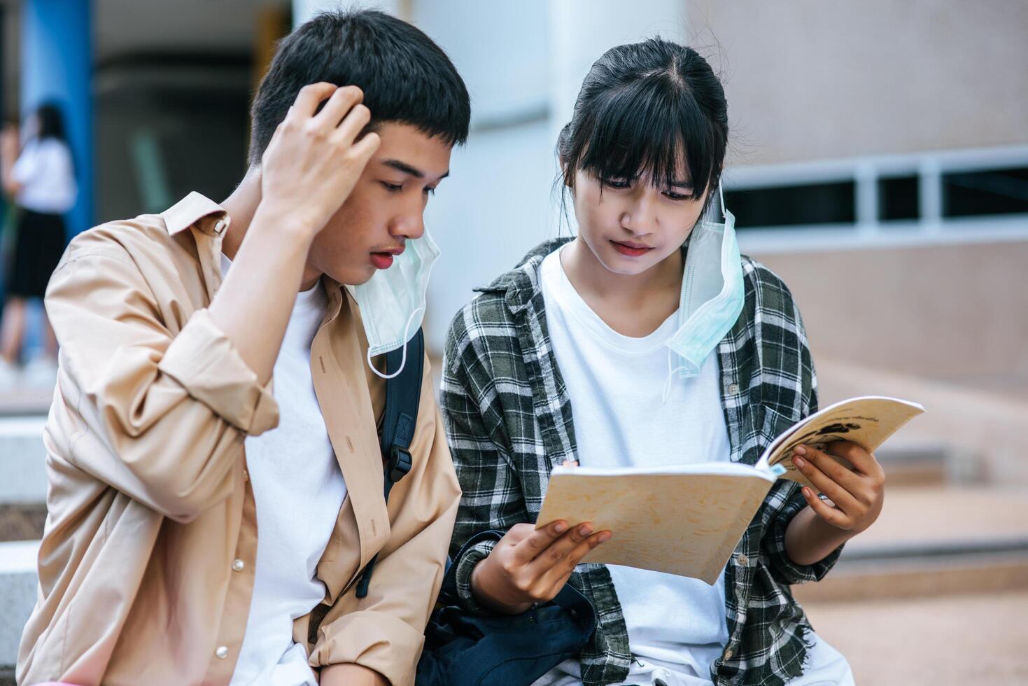 estudiantes masculinos y femeninos sentados y leyendo libros en las escaleras. foto