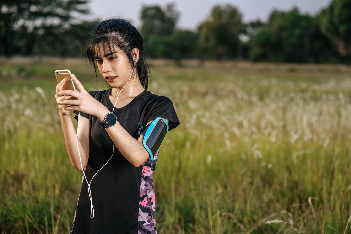 A woman stands relaxed after exercising on the street and playing a smartphone. photo