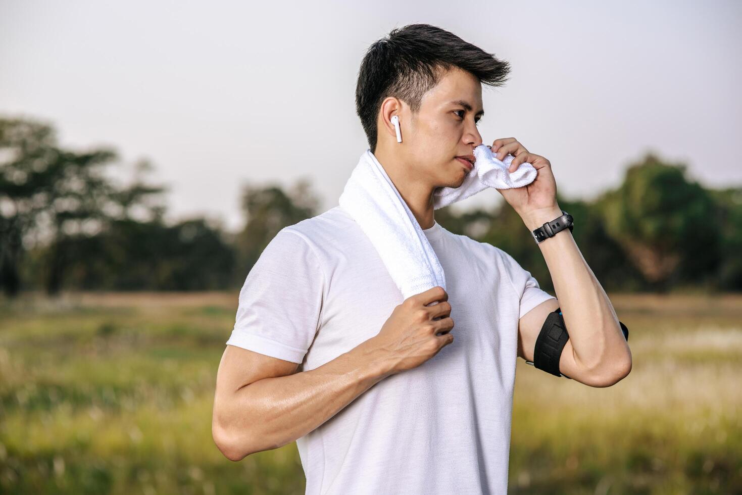 un hombre con camisa blanca se puso de pie y se cubrió el cuello con un pañuelo para secarse la cara. foto