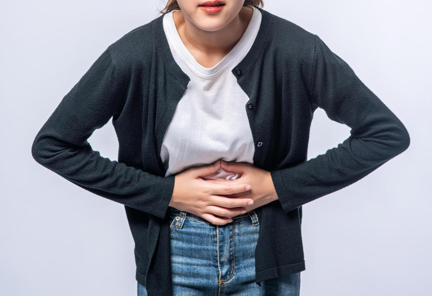 una mujer de pie con dolor de estómago y presiona su mano sobre su estómago. foto