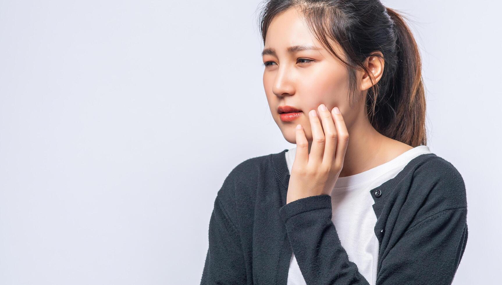 A woman sick with a toothache and a hand holding on the cheek photo