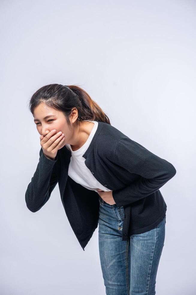 A woman with a stomachache puts her hands on her stomach and covers her mouth. photo