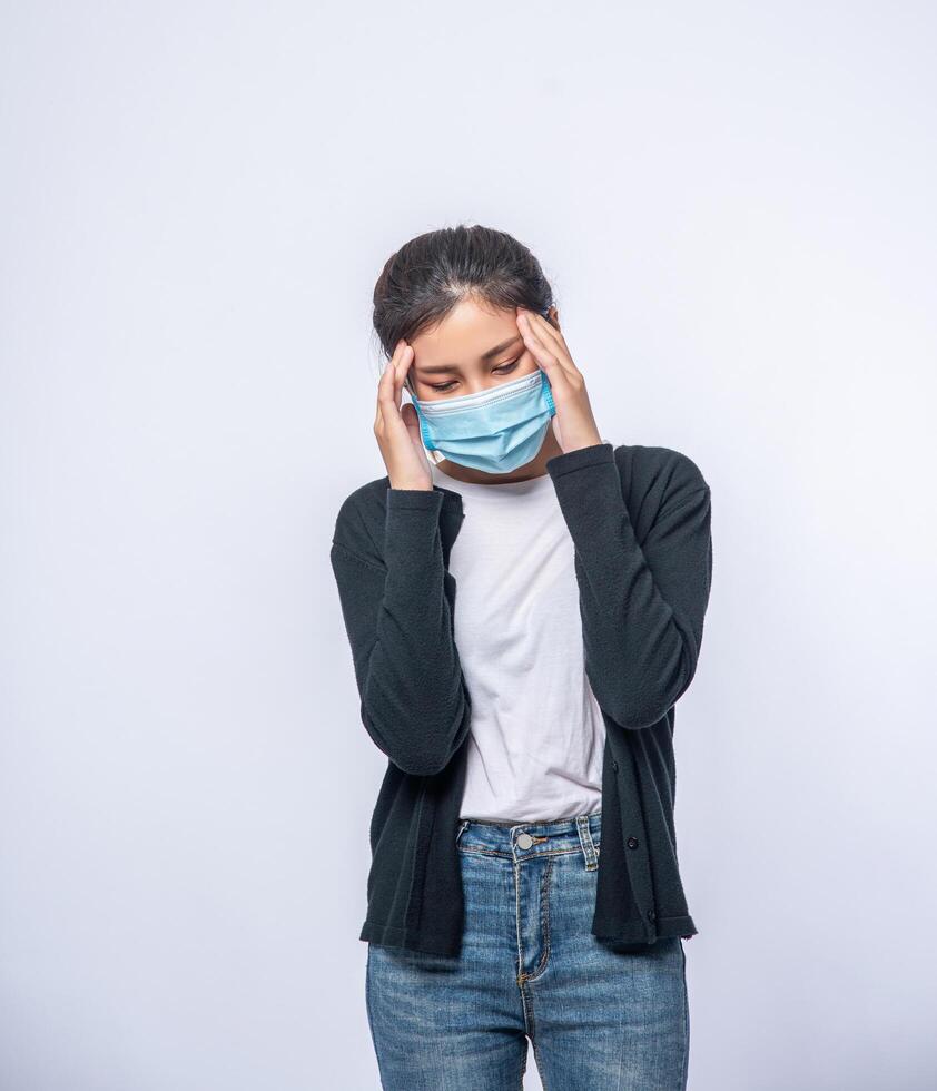 A sick woman with a headache wore a mask and placed a hand on her head. photo