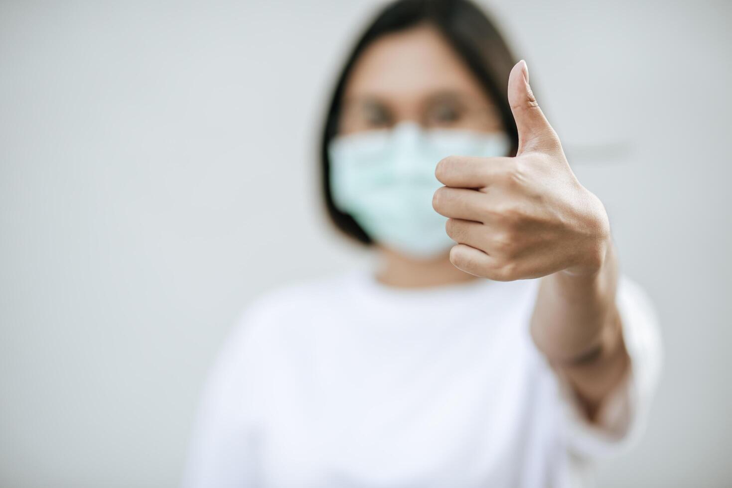 The women wear masks and mark them with their thumbs up. photo