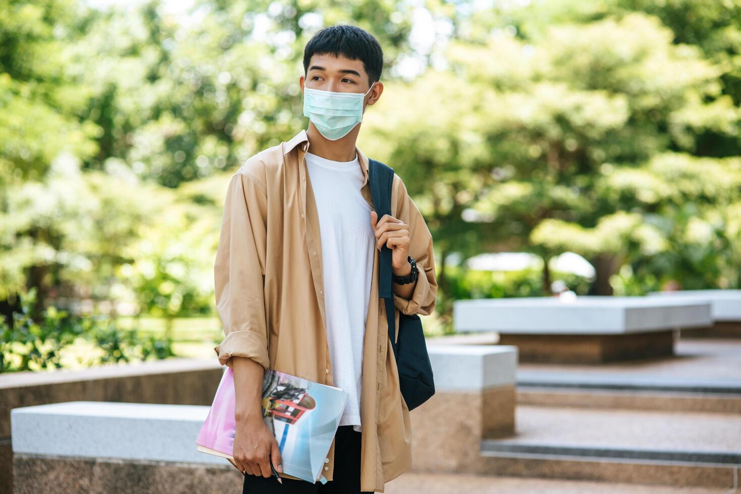 Men wear masks, carry books, and carry a backpack on the stairs. photo