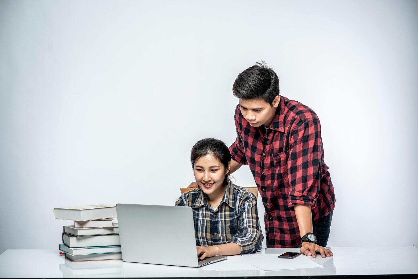 Men teach women how to work with laptops at work. photo
