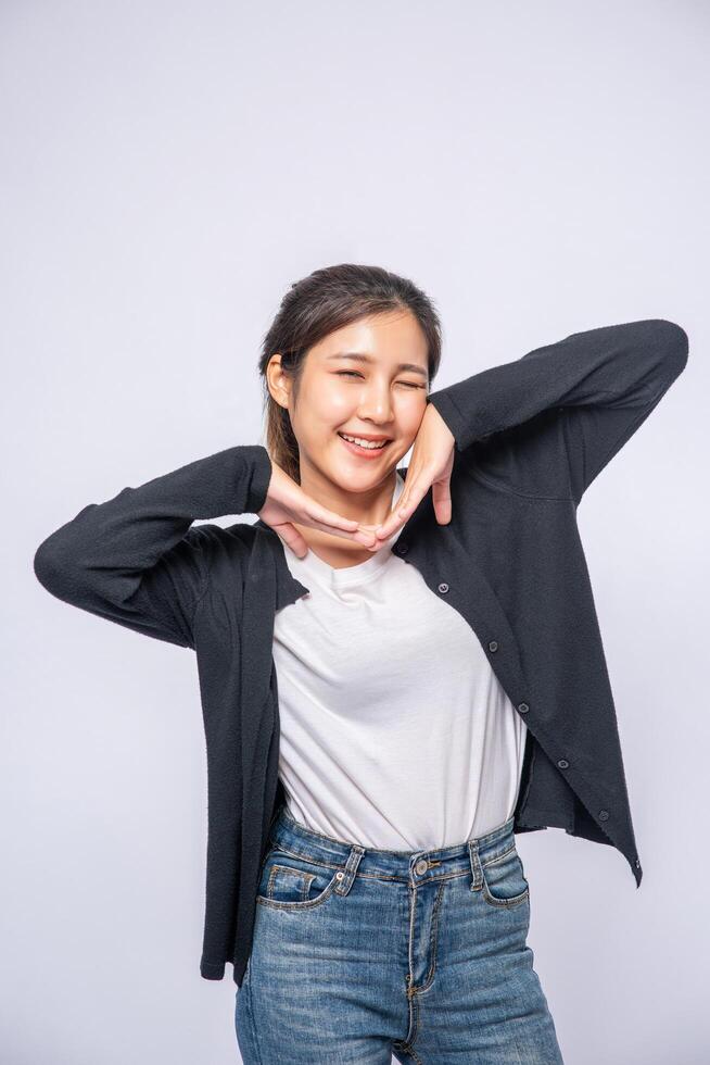 una mujer sonriente felizmente con una camisa negra, jeans de pie, sonriendo felizmente. foto