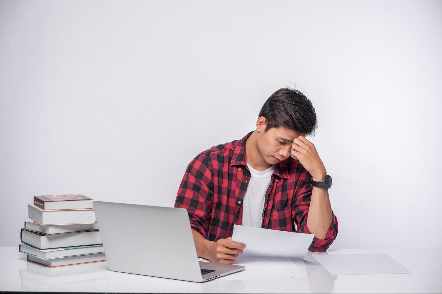 A man using a laptop in the office and doing a document analysis. photo