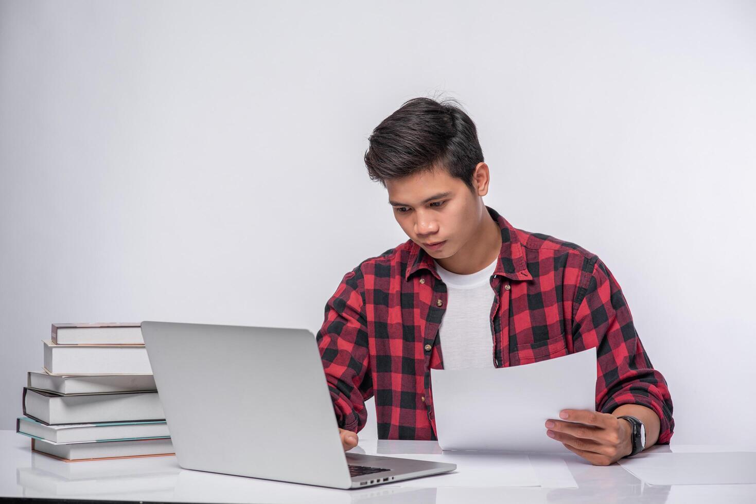 A man using a laptop in the office and doing a document analysis. photo