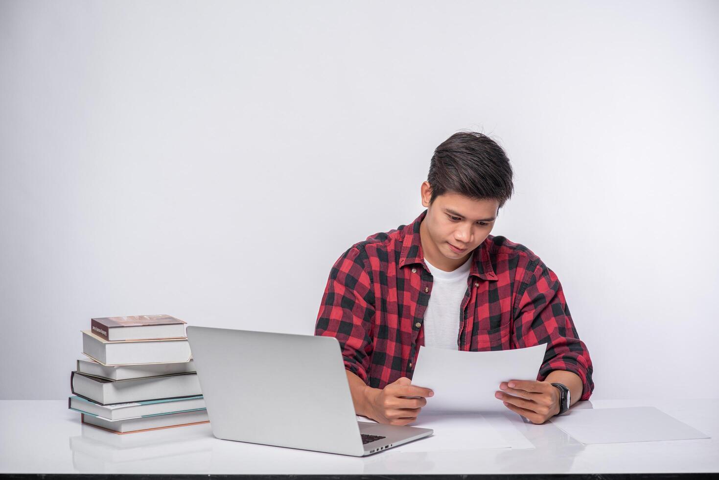 A man using a laptop in the office and doing a document analysis. photo