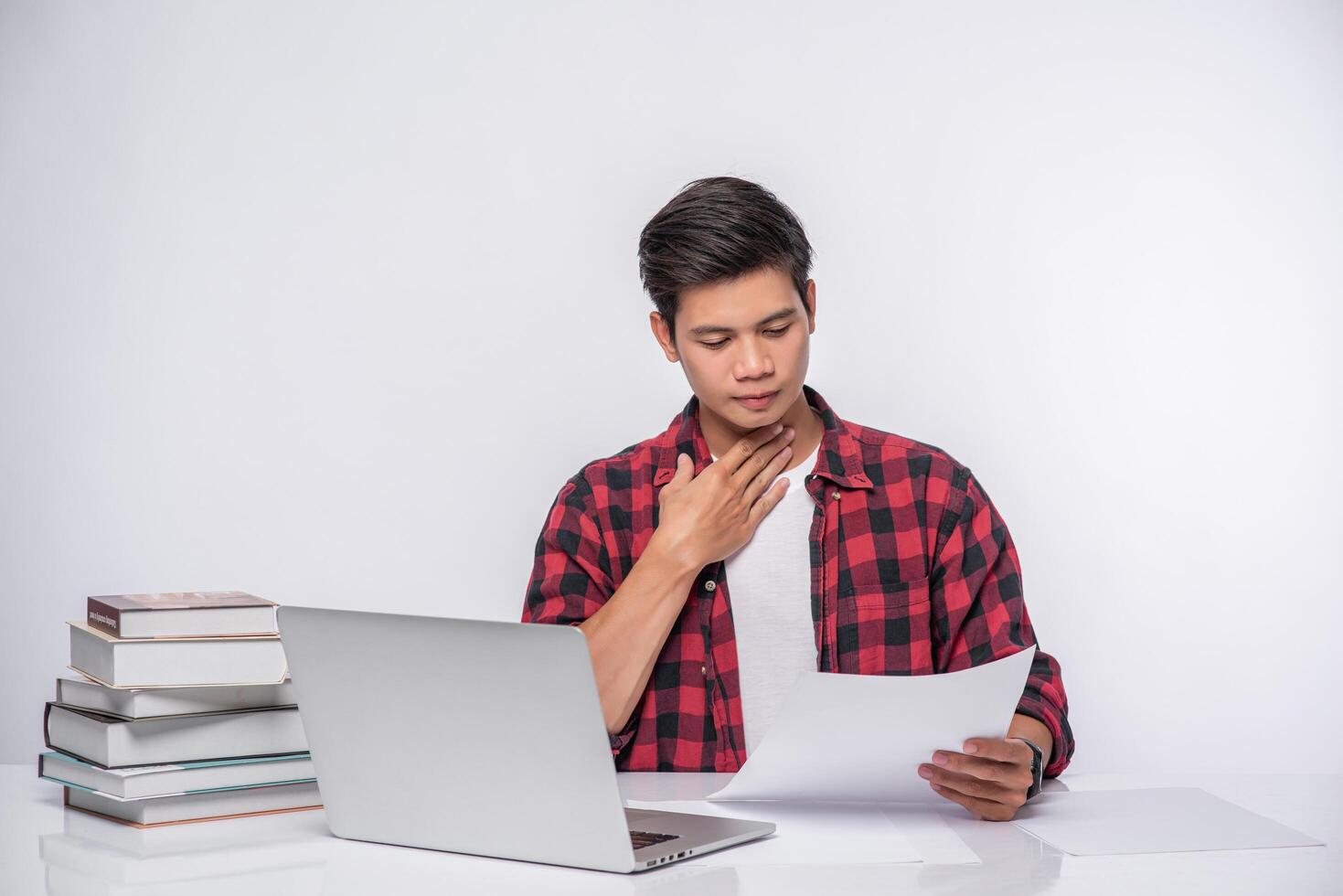 A man using a laptop in the office and doing a document analysis. photo