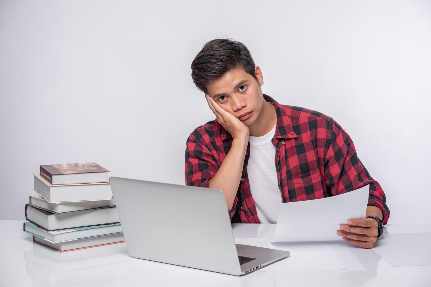A man using a laptop in the office and doing a document analysis. photo