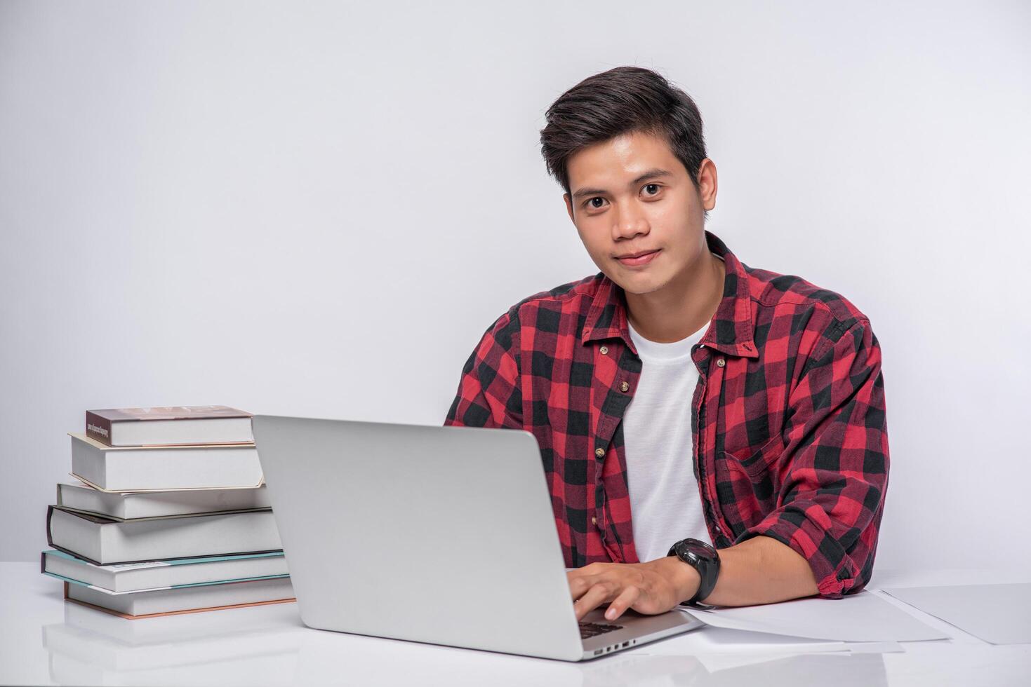 A man wearing a striped shirt uses a laptop to work. photo