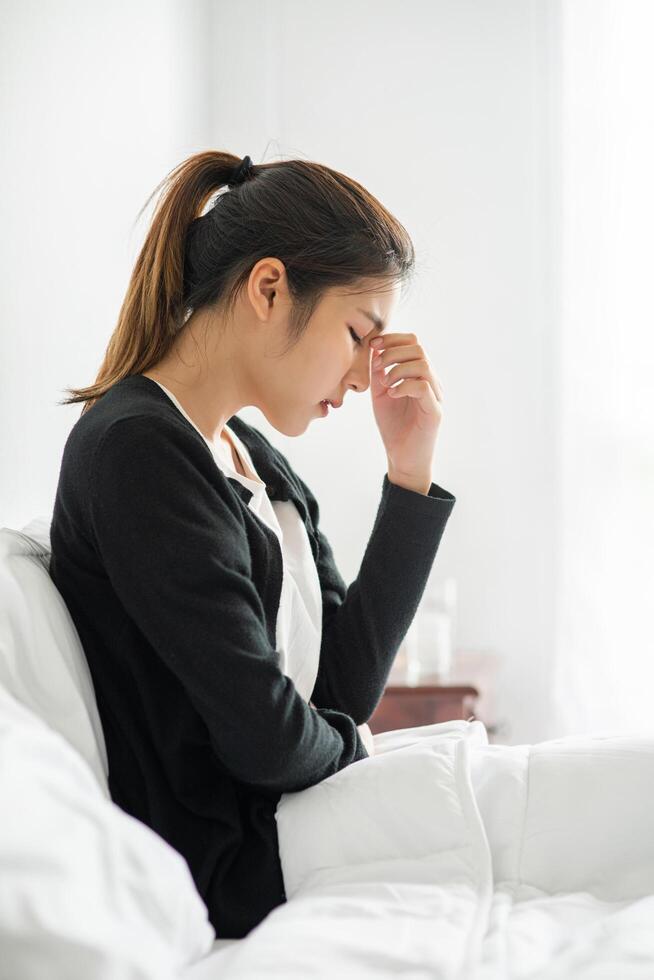 The sick woman had a headache and put her hand on her nose on the bed. photo