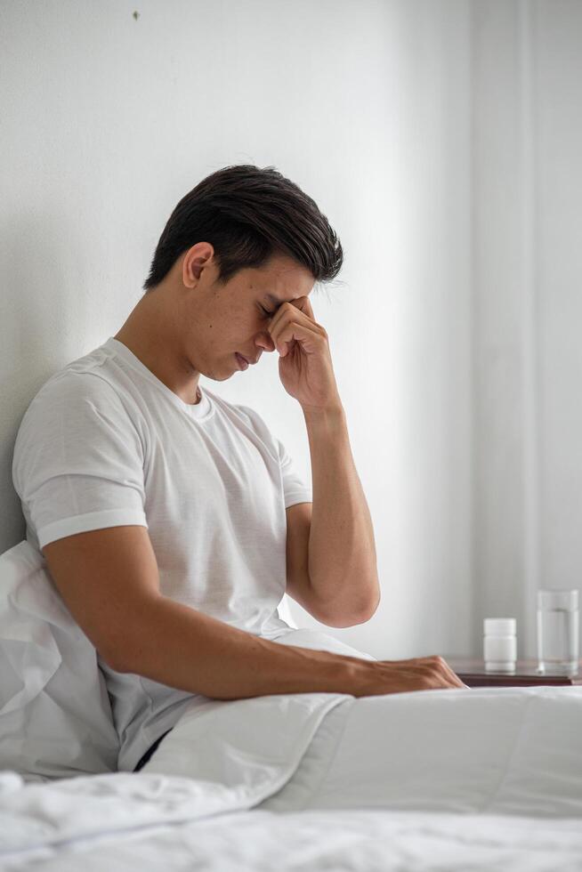 The sick person sat on the bed with his hands and held his nose. photo