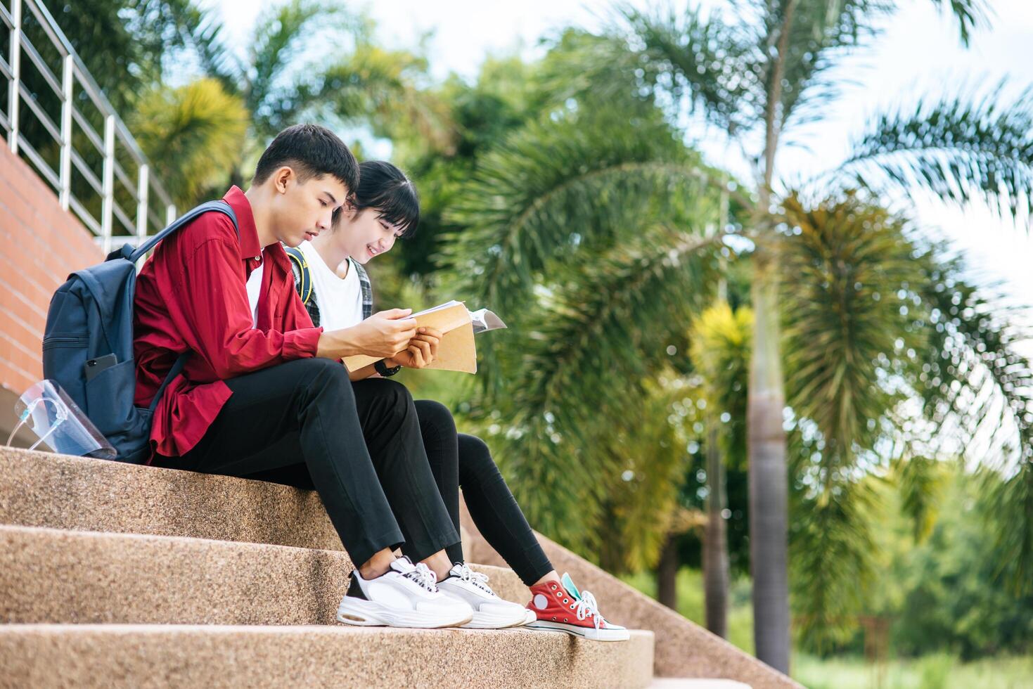 Male and female students sitting and reading books on the stairs. photo