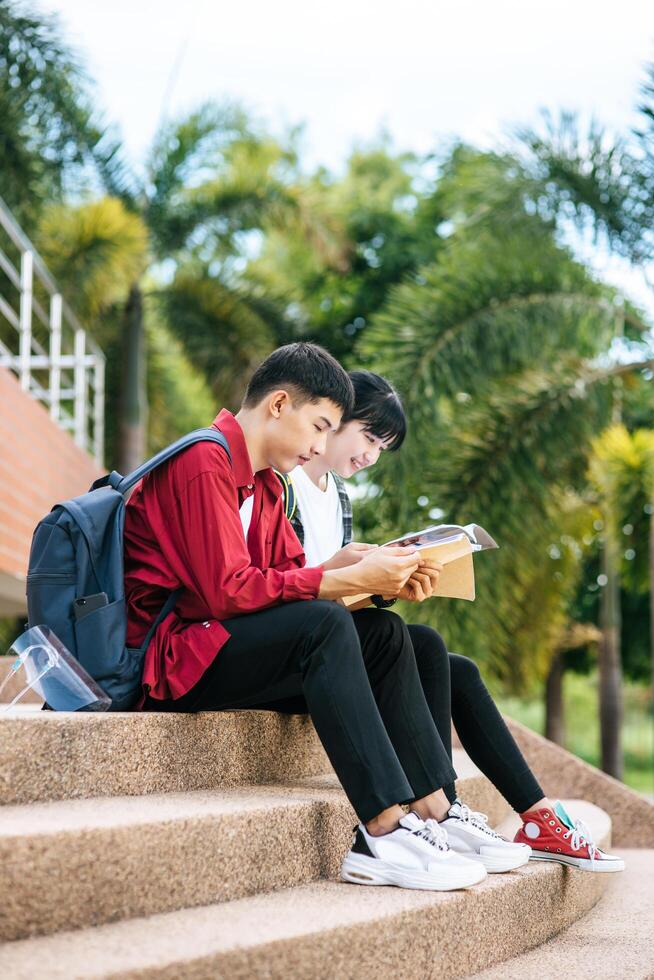 estudiantes masculinos y femeninos sentados y leyendo libros en las escaleras. foto