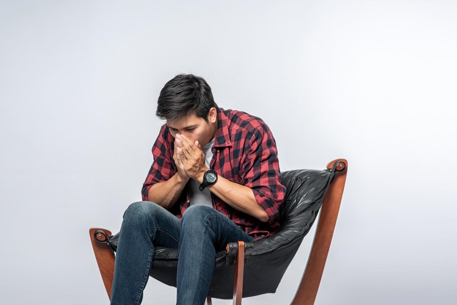 The man in a striped shirt sits sick and sits on a chair and crosses his arms. photo