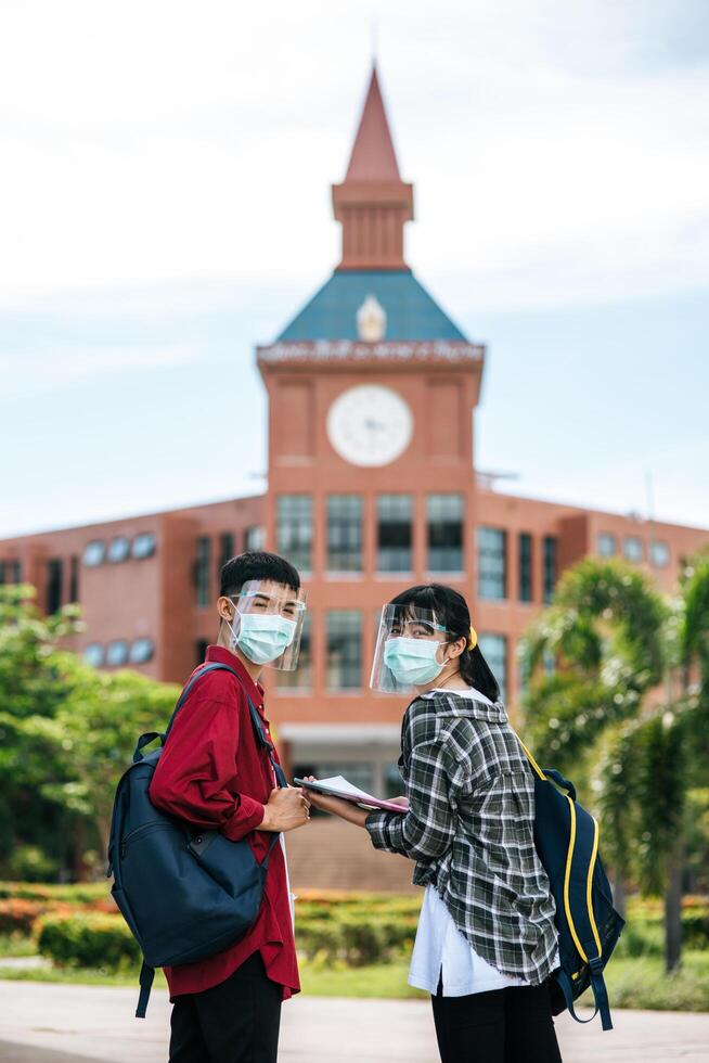 los estudiantes masculinos y femeninos usan máscaras y se paran frente a la universidad. foto