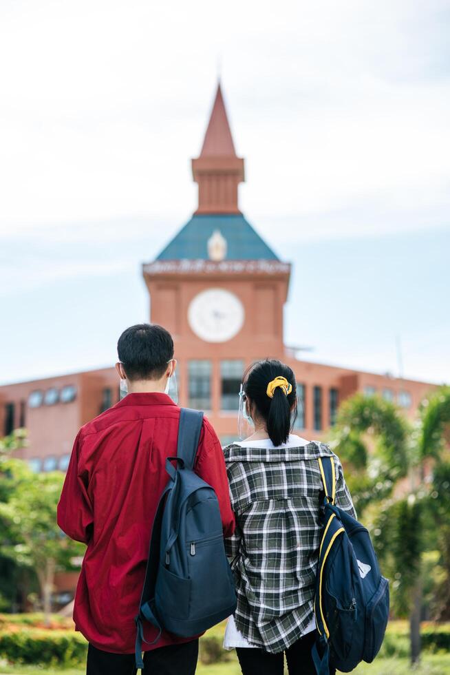 Male and female students wear masks and stand in front of the university. photo