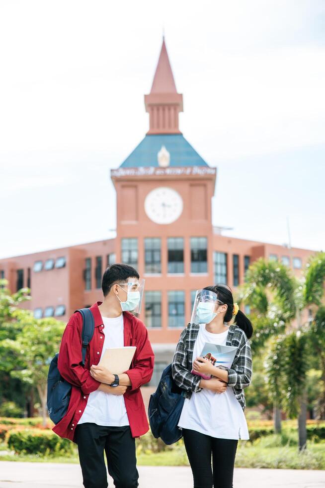 Male and female students wear masks and stand in front of the university. photo