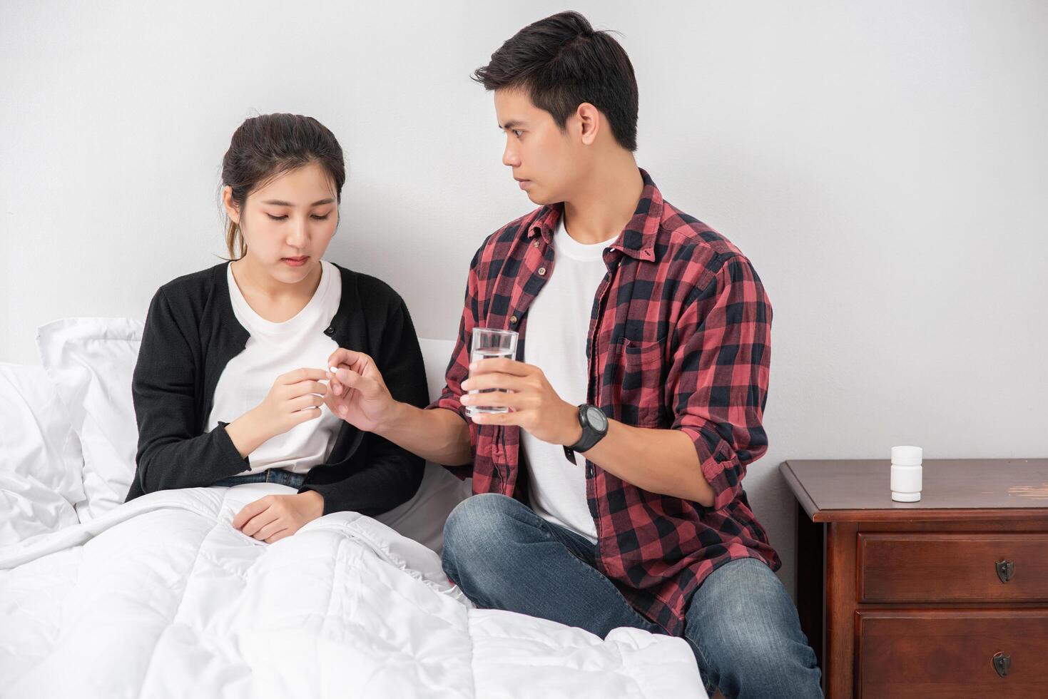 A man handed medicine to a sick woman in bed. photo