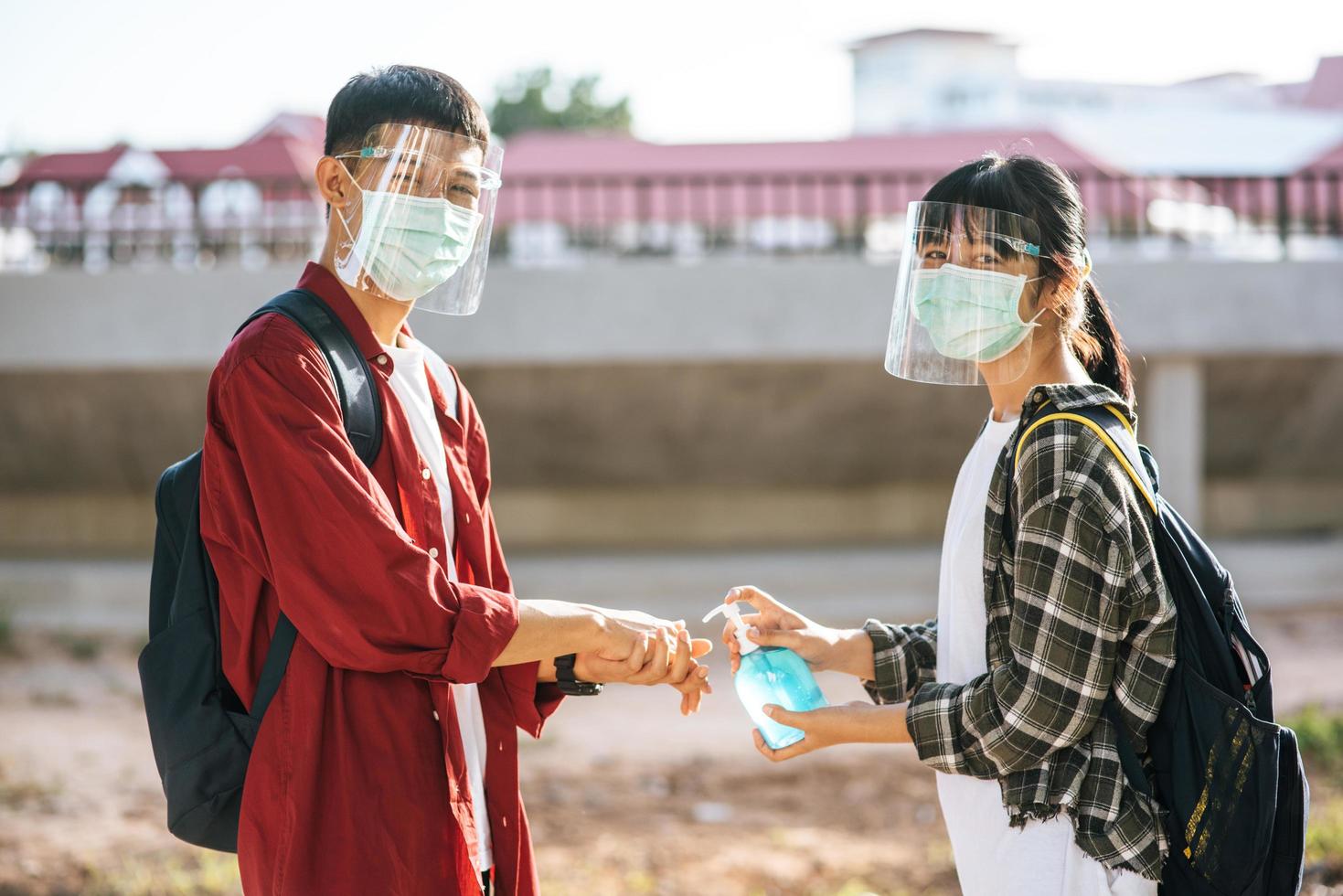 Male and female students wear masks and squeeze the gel to wash their hands. photo
