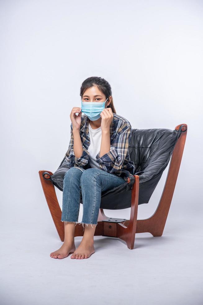 An uncomfortable woman sitting on a chair and wearing a mask photo
