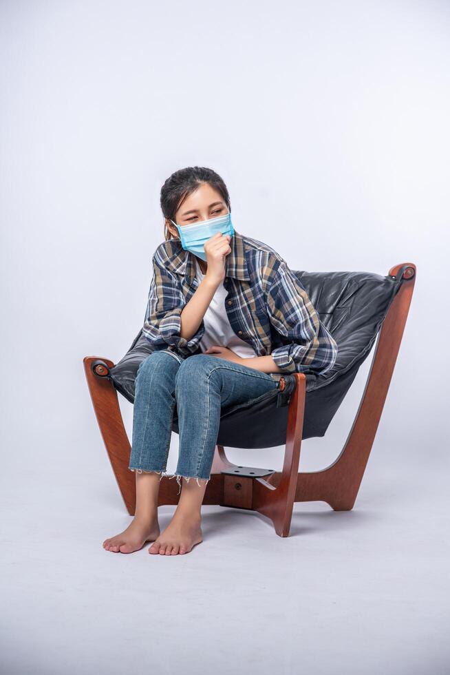 Una mujer incómoda sentada en una silla y con una máscara. foto