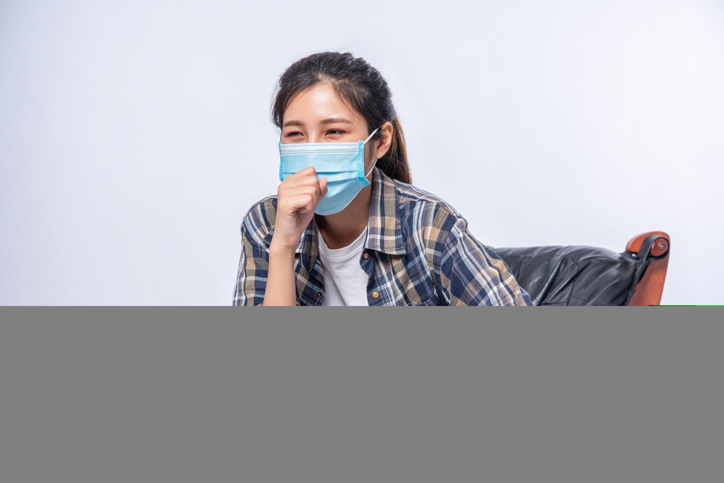 An uncomfortable woman sitting on a chair and wearing a mask photo