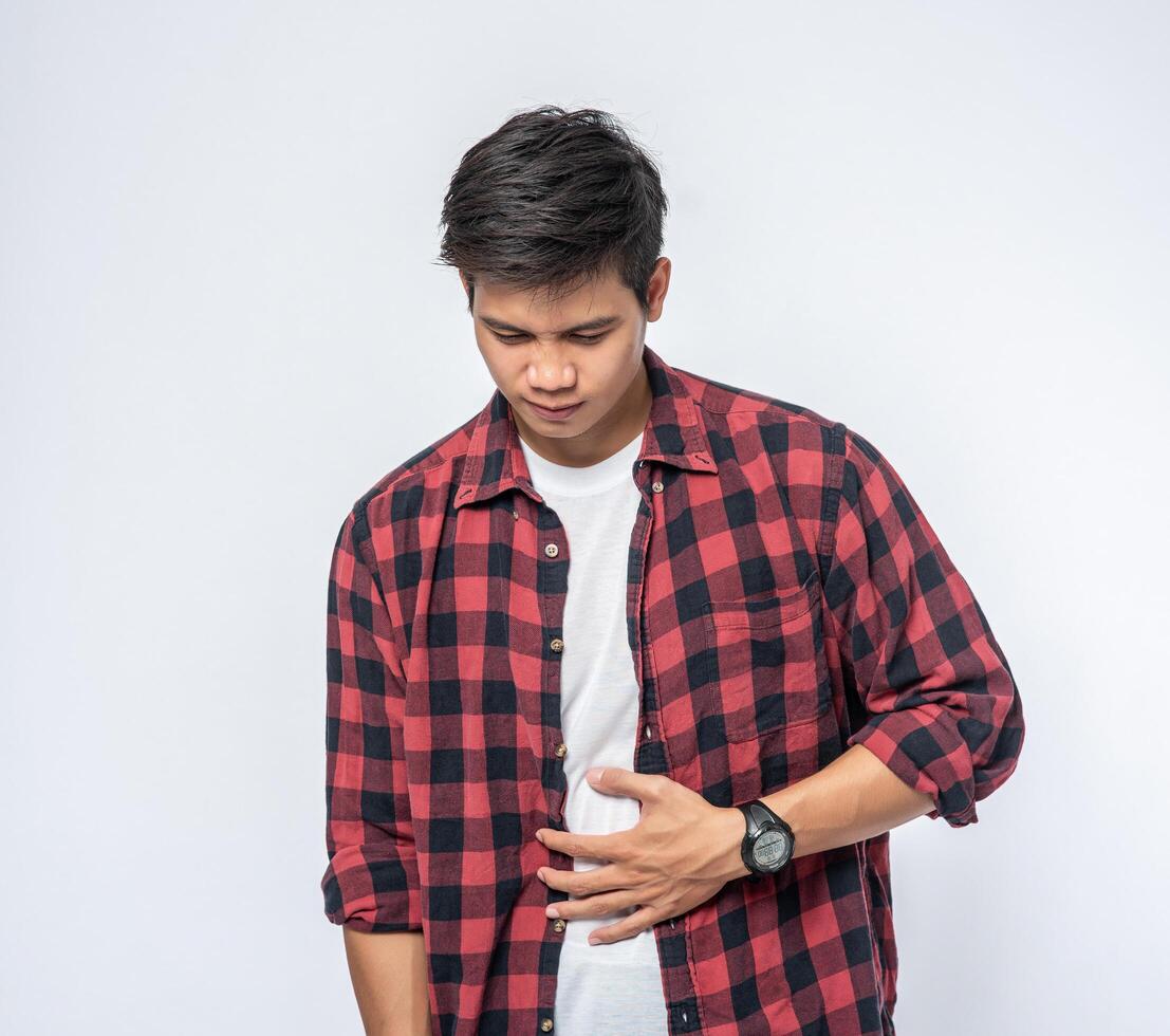 A man stands with a stomachache and puts his hand on his stomach. photo