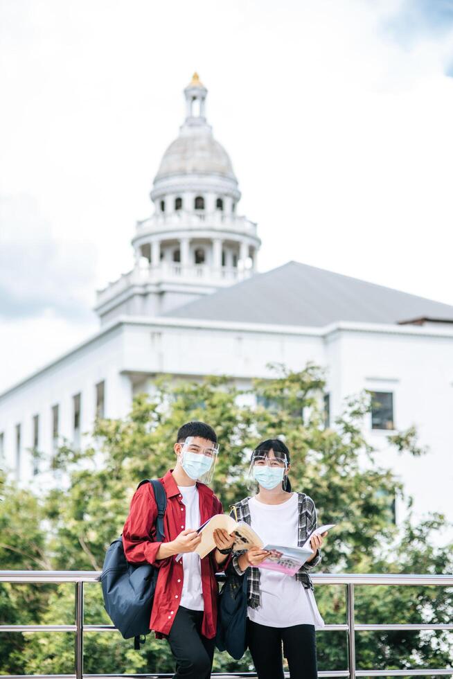 Male and female students wear masks and stand to talk on the balcony. photo