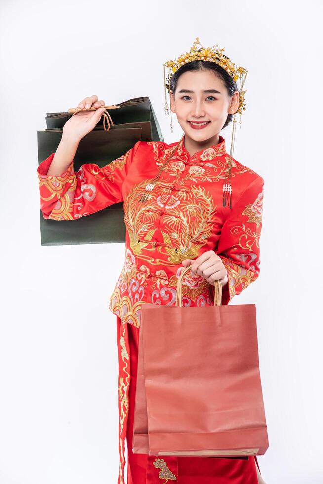 Mujer vistiendo traje cheongsam sonrisa con bolsa de papel de compras en año nuevo chino foto