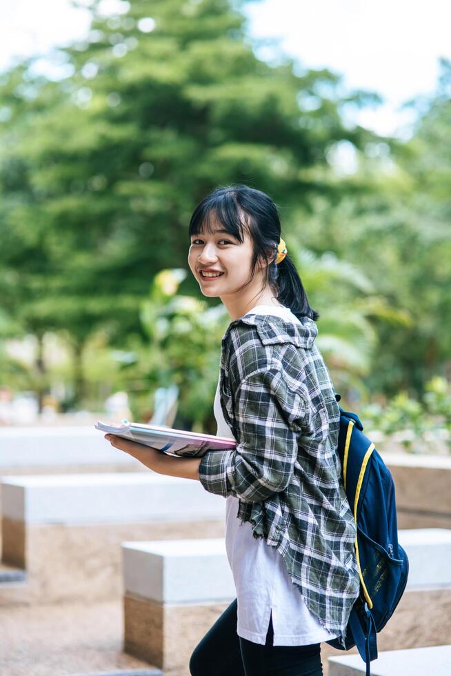 Female students stand on the stairs and hold books. photo