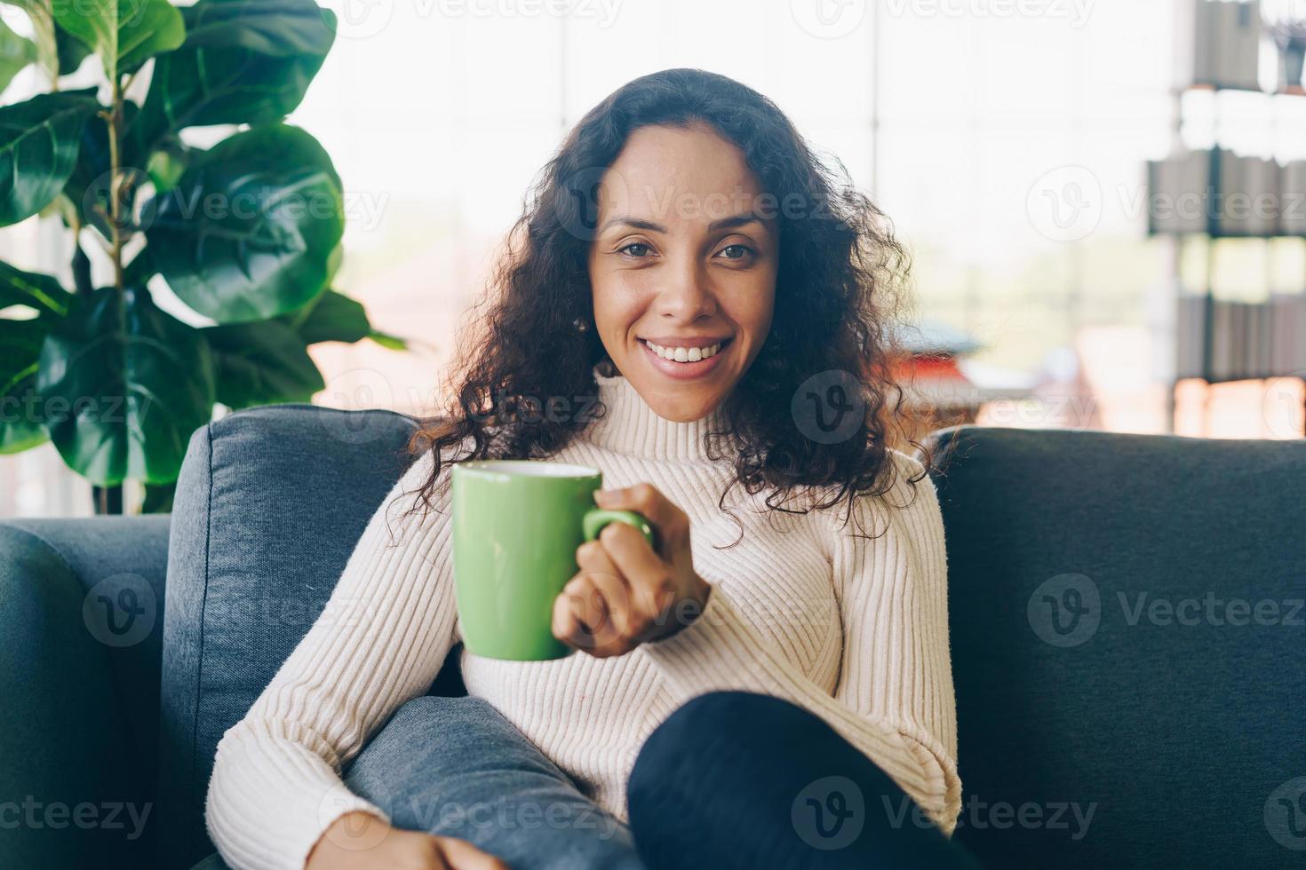 mujer latina tomando café en el sofá foto