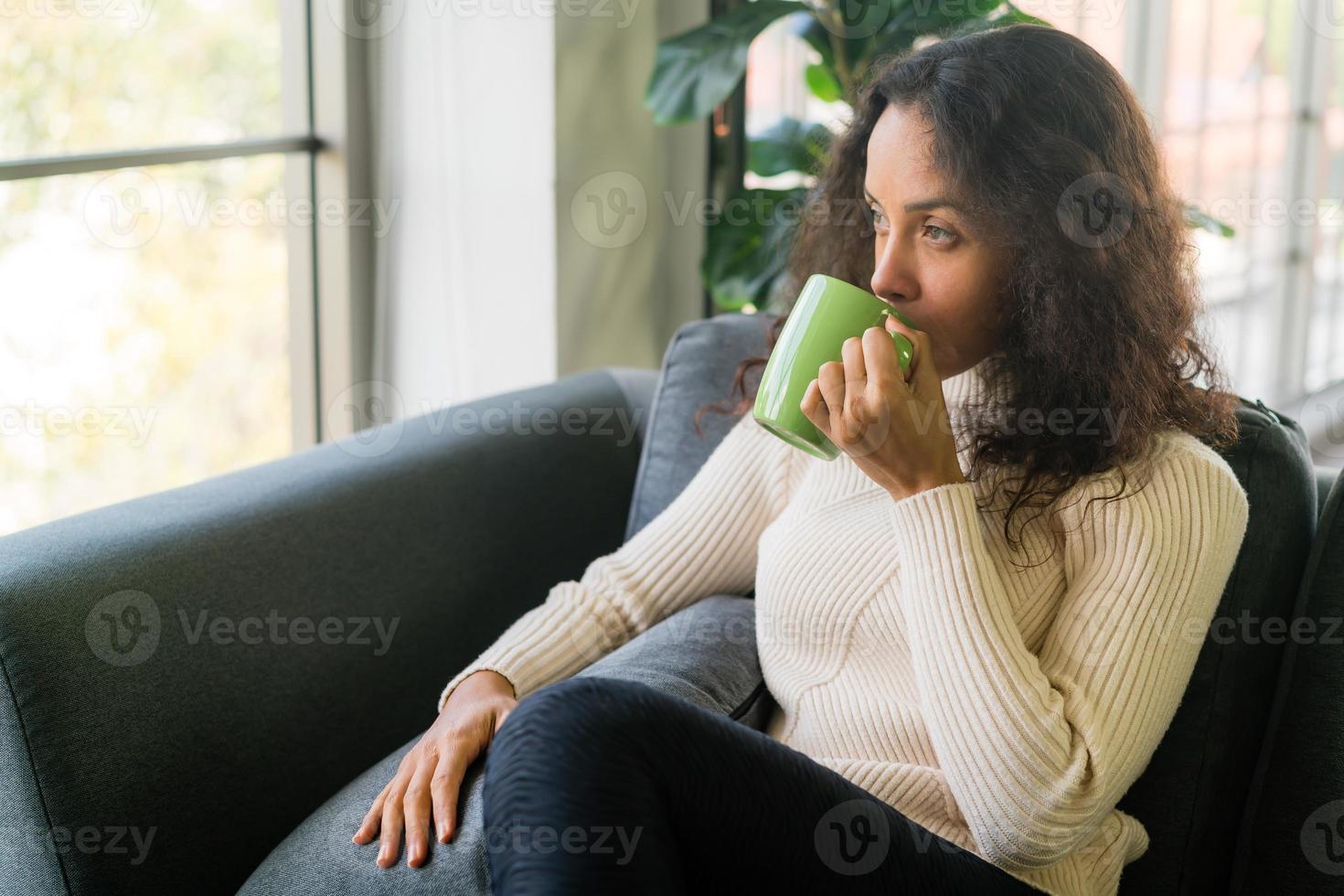 mujer latina tomando café en el sofá foto