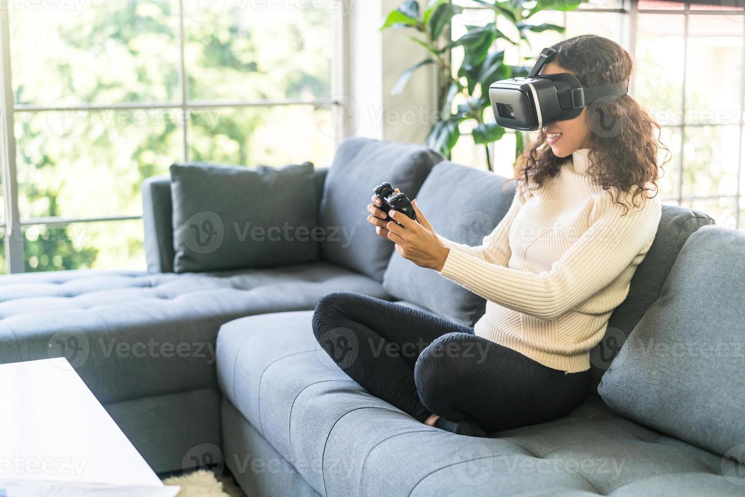 Latin woman using a virtual reality headset on sofa photo