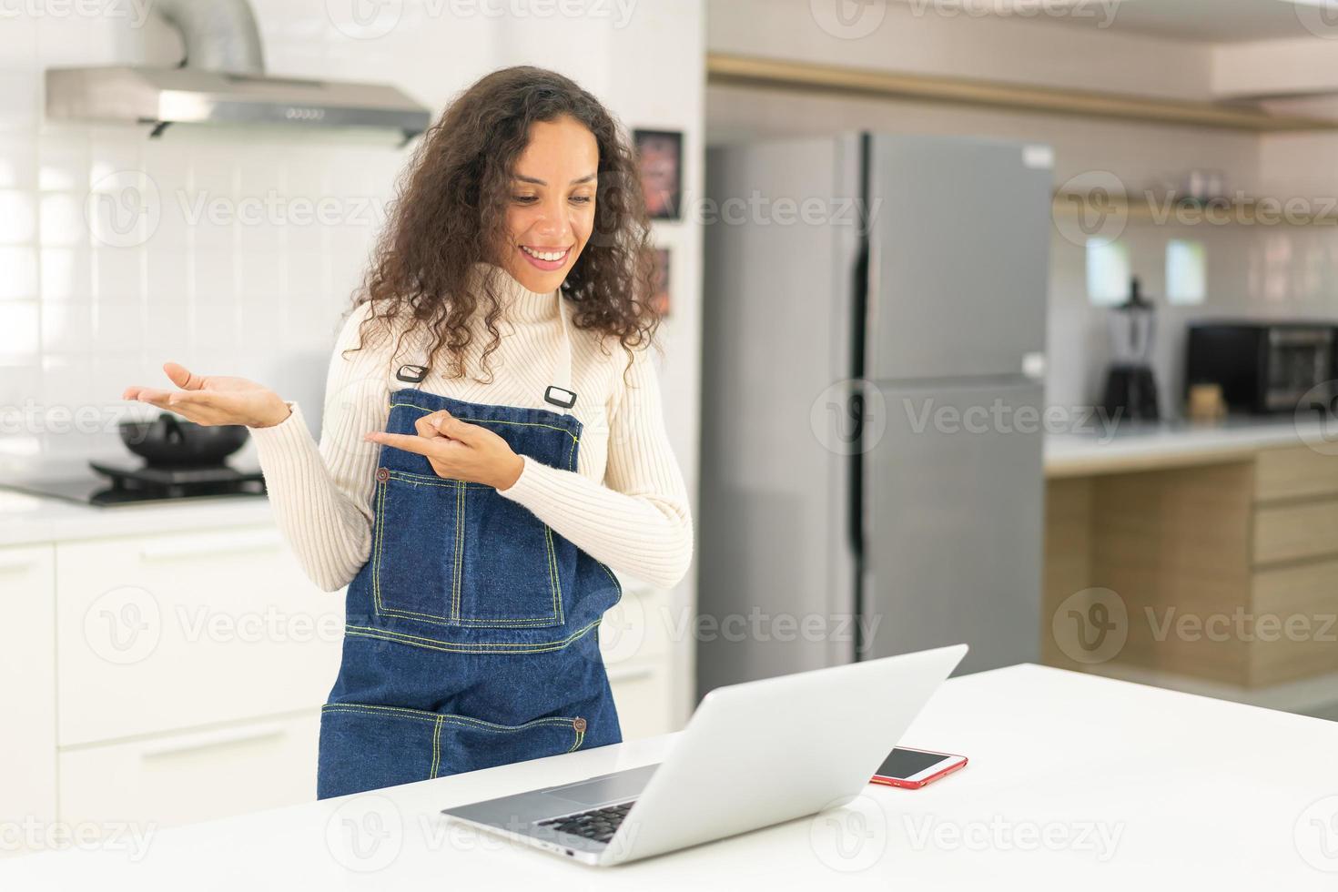 Latin woman shooting video and cooking at the kitchen photo