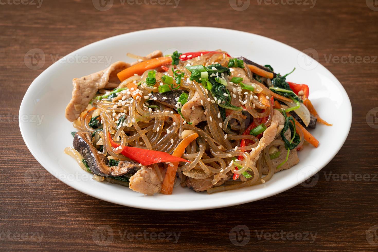 japchae or stir-fried Korean vermicelli noodles with vegetables and pork topped with white sesame photo