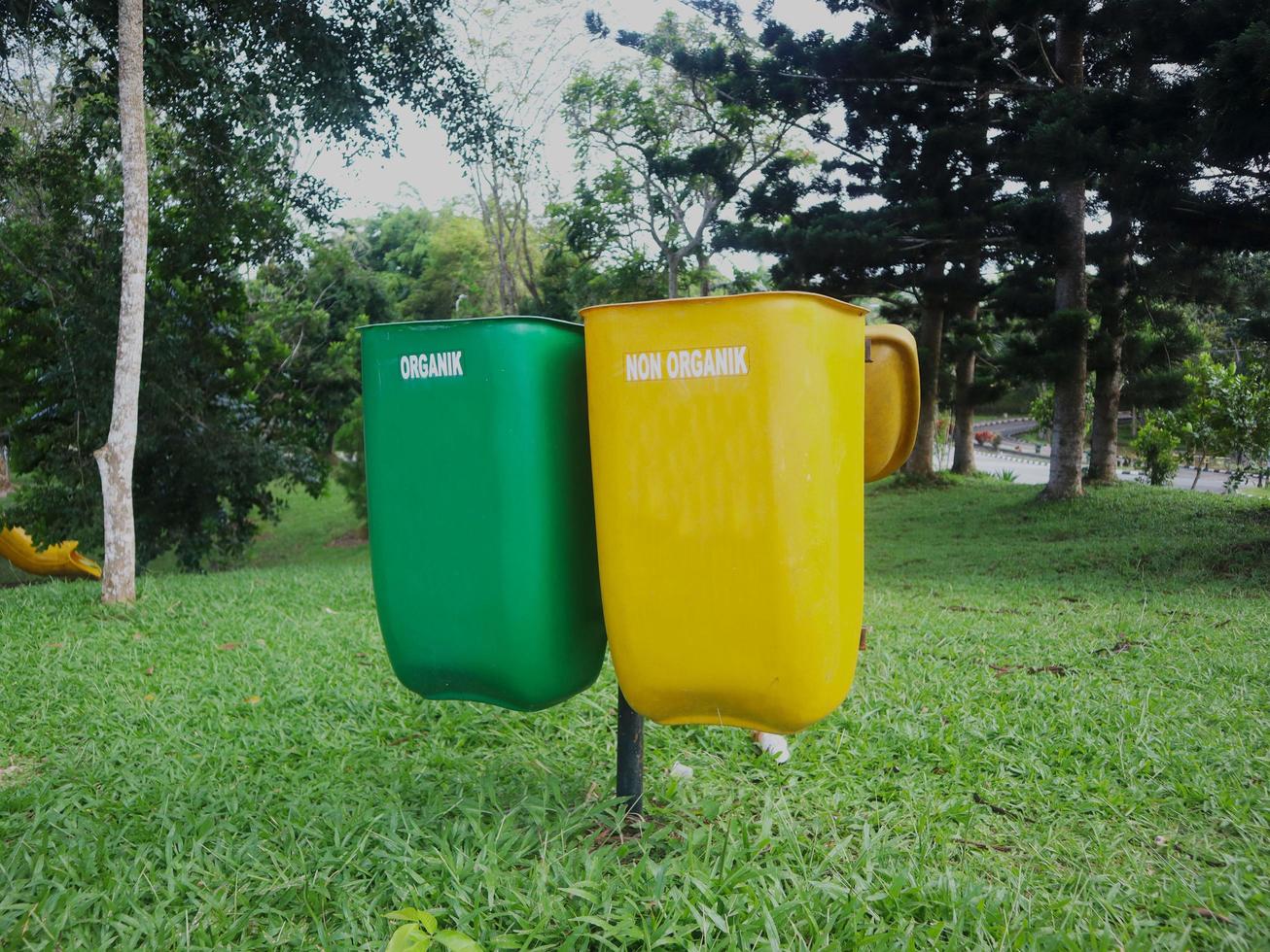 yellow bins for non-organic waste that cannot be recycled, and green for recyclable organic waste. placed in a park photo