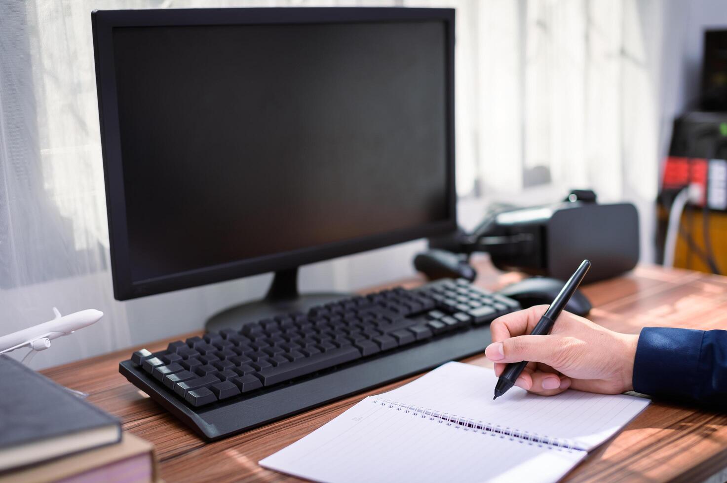 A person is writing on a notepad while sitting at a desk photo