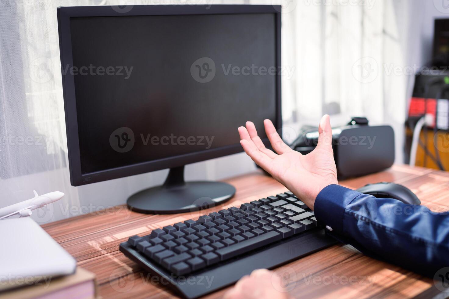 A person is sitting at a desk with a computer and a keyboard photo