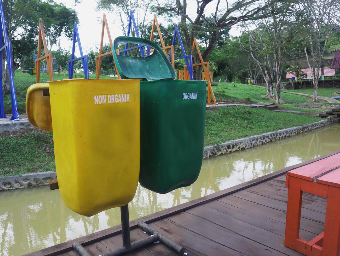 yellow bins for non-organic waste that cannot be recycled, and green for recyclable organic waste. placed in a park photo