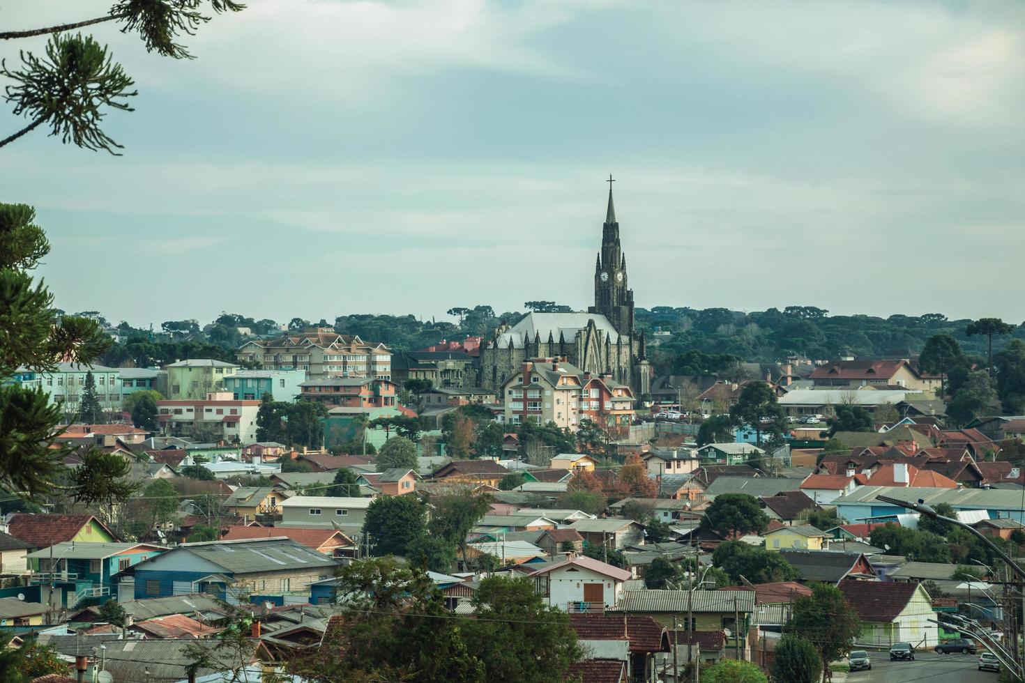 canela, brasil - 21 de julio de 2019. calle con coches que van hacia el paisaje urbano de casas y campanario en canela. un pequeño pueblo encantador muy popular por su ecoturismo. foto