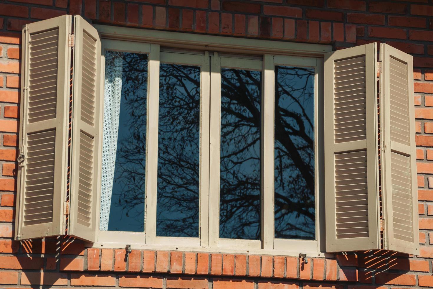 Bento Goncalves, Brazil - July 11, 2019. Glazed window with open shutters in a country house with brick wall, on a farm near Bento Goncalves. photo