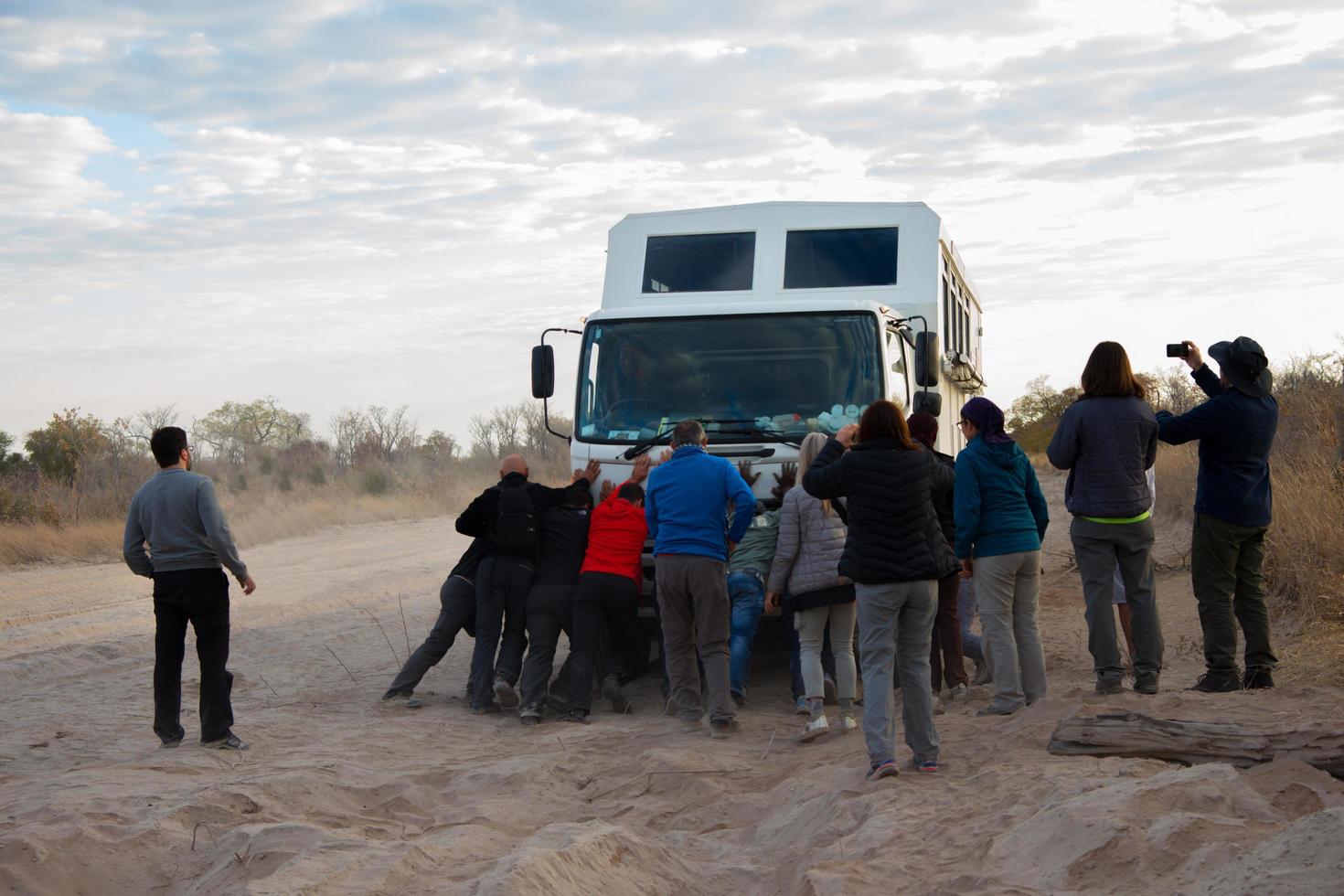 Kalahari desert, Namibia, 2016, Group of tourists helping their truck to get through a sandy road. Cloudy sky, copy space. Kalahari region, Namibi photo