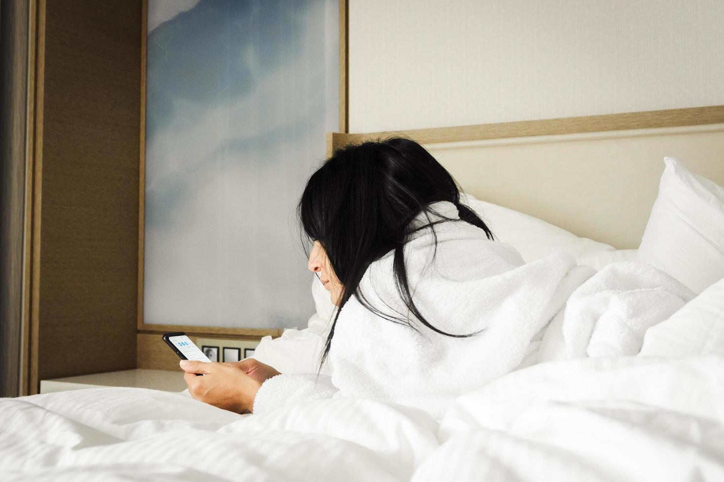 mujer en la cama revise el teléfono foto