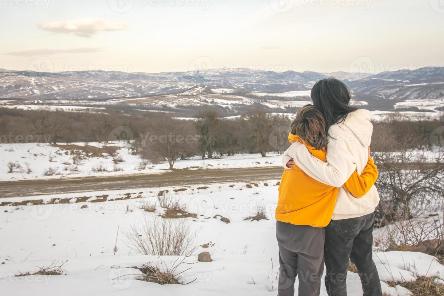 Young mother hugs teenager son with spring panorama background. Parenthood and togetherness concept photo