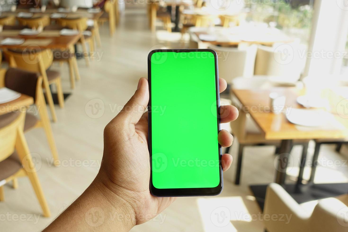 Close up of young man hand using smart phone with green screen photo